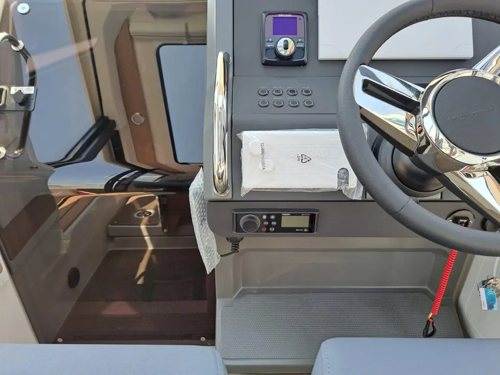 Boat dashboard featuring a steering wheel, control panel, and a display screen, with visible "SIMRAD" branding on the device.